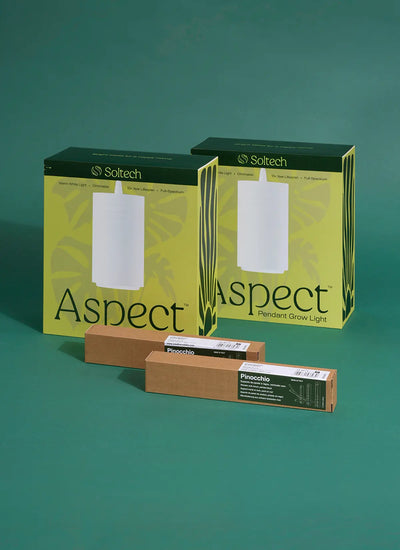 Two boxes of Soltech white Aspect Gen 2 grow lights with their contents displayed in front, including the lights themselves, wall mounts, and Pinocchio accessories against a green background.