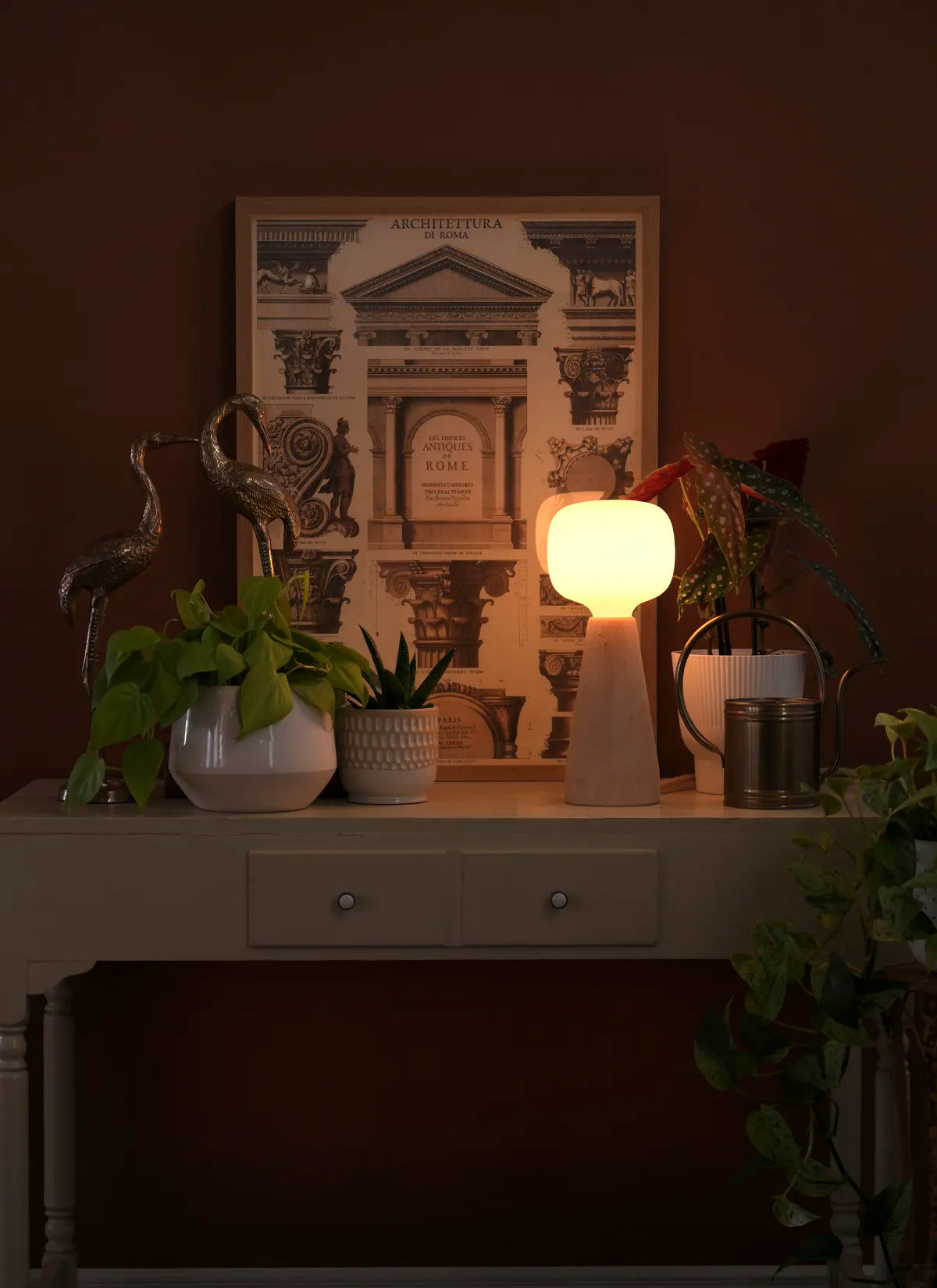 Decorative table with a Soltech Aura, plants, and a framed picture on a dark background.