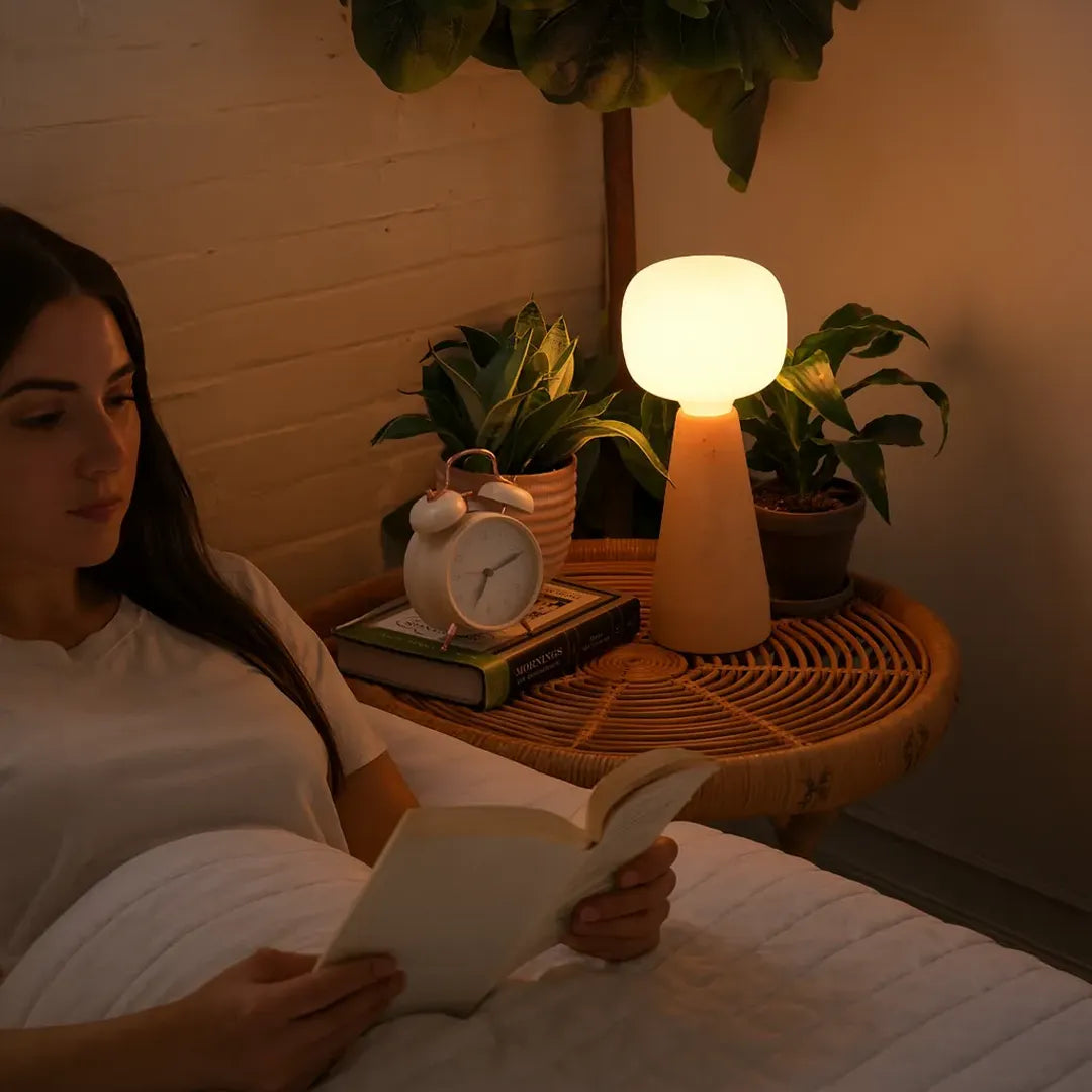 Woman reading a book in bed with a Soltech Aura on a bedside table.