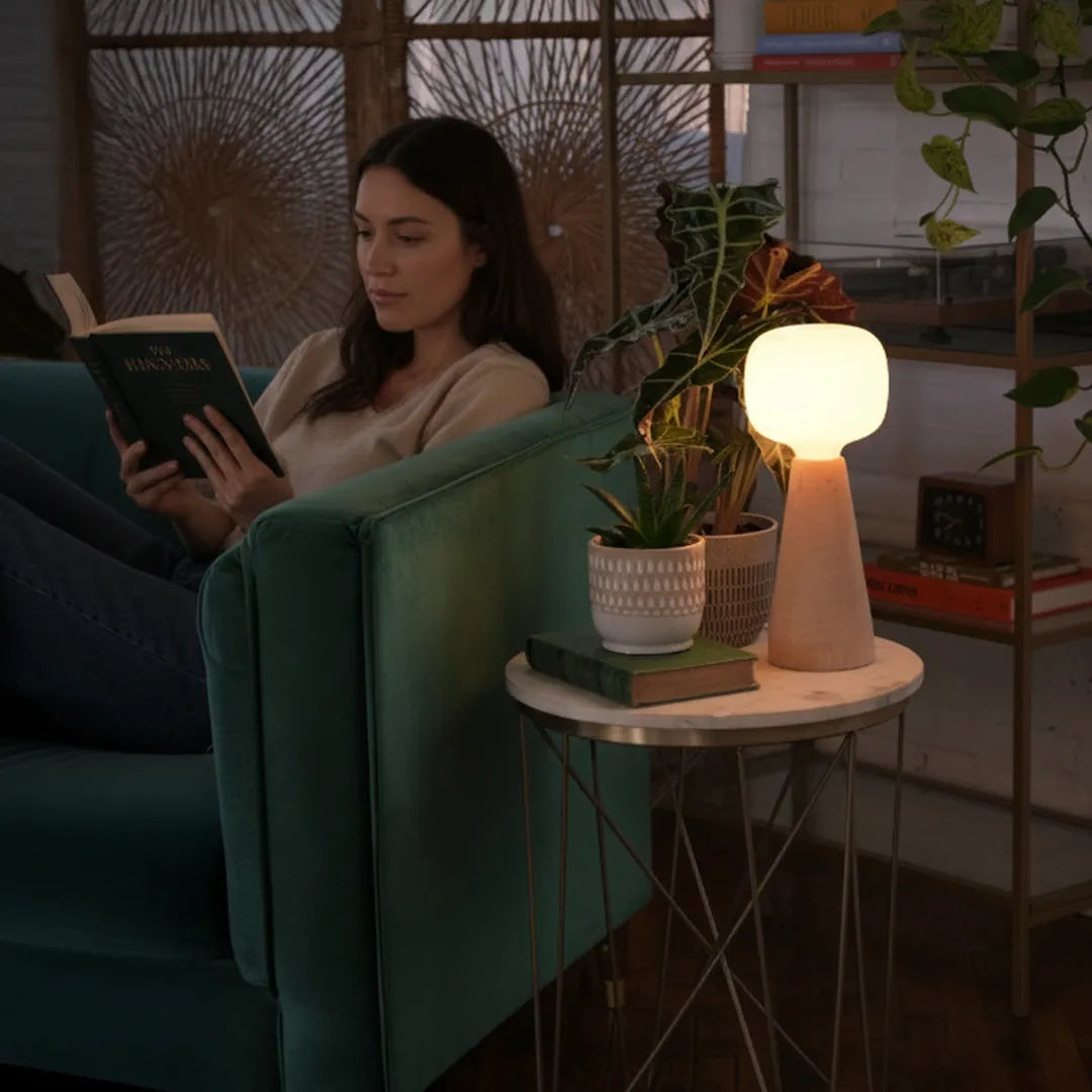 Woman reading a book in a cozy living room with a Soltech Aura and plants.