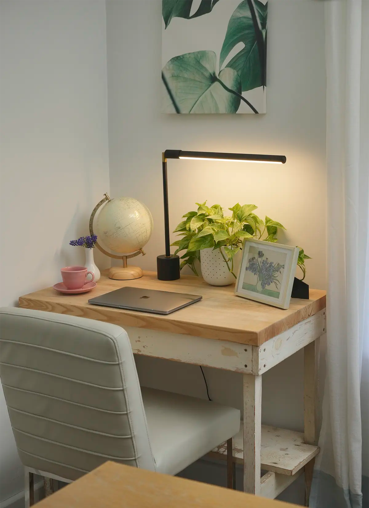 Small wooden desk with a chair, black Soltech Versa, plant, and decor items in a room.