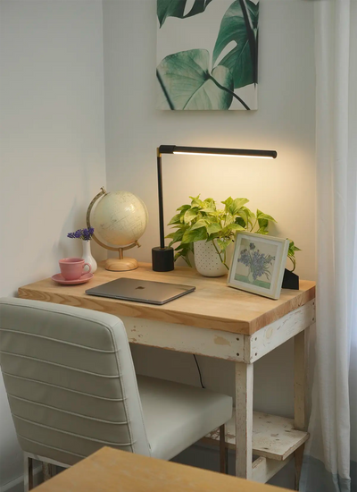 Small wooden desk with a chair, black Soltech Versa, plant, and decor items in a room.