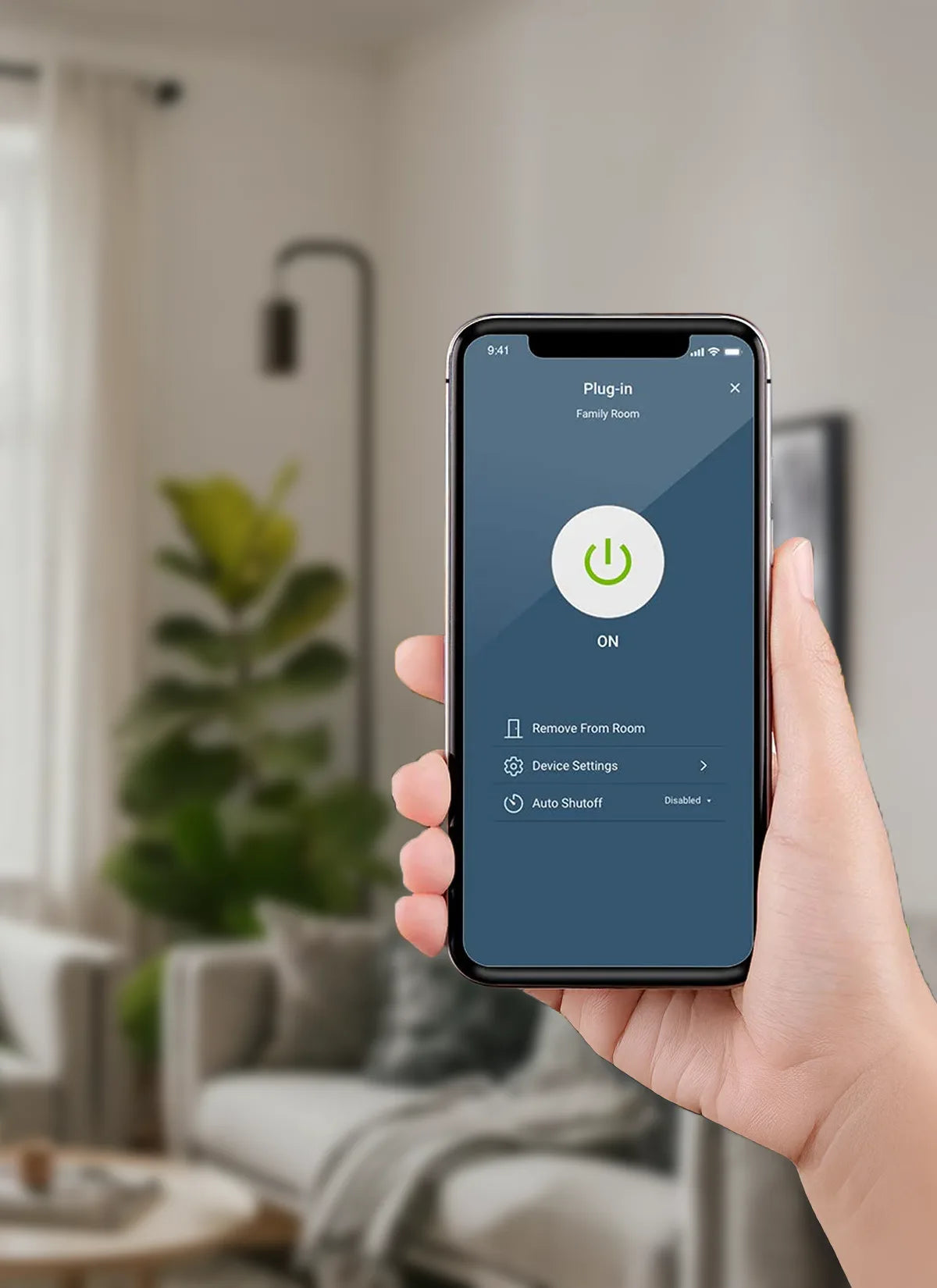 Hand holding a smartphone with an app displaying a power icon, set against a blurred living room background.