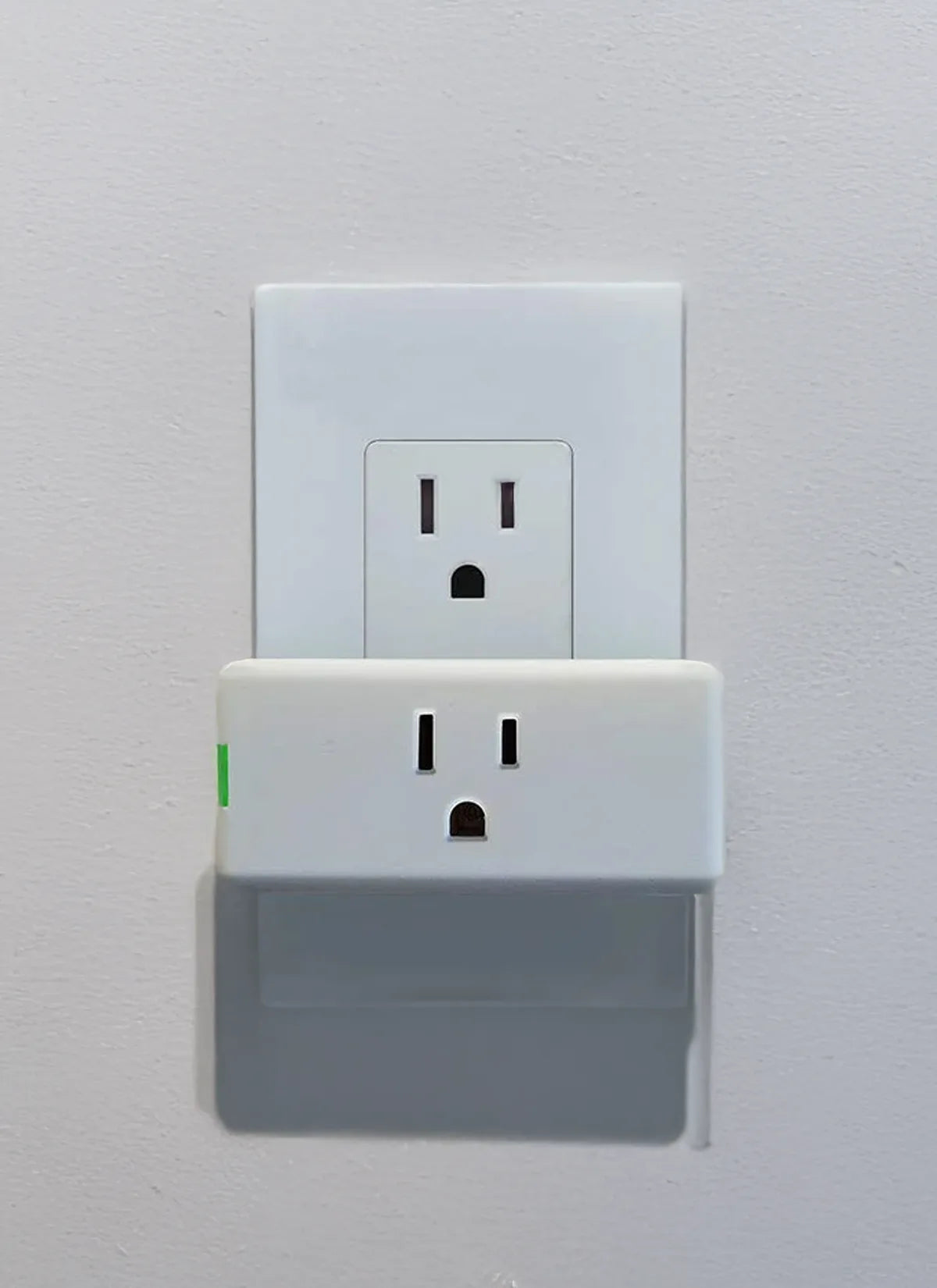 White electrical outlet with Leviton plugged in light on a gray wall.