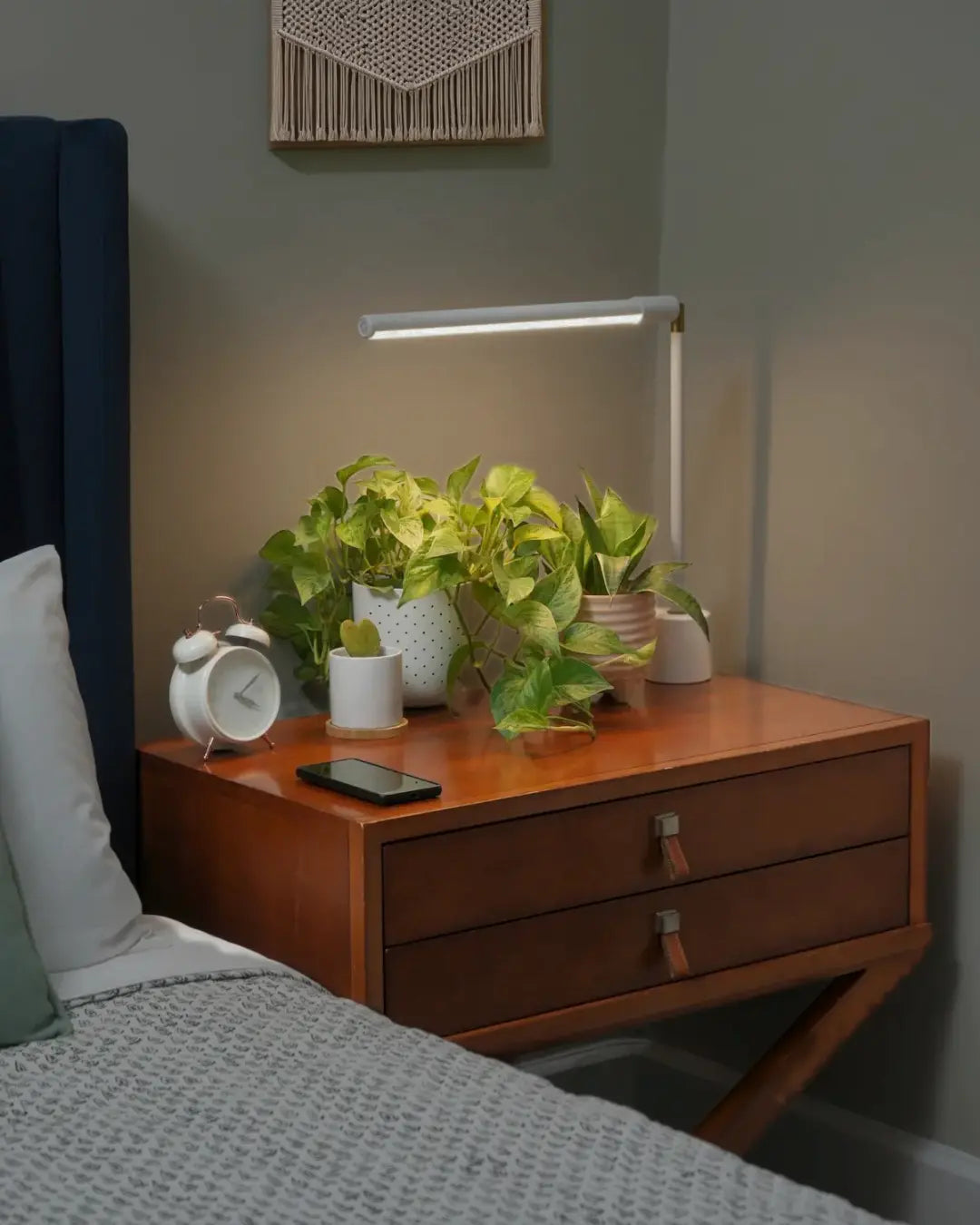 Wooden nightstand with plants, clock, white Soltech Versa and phone in a bedroom setting