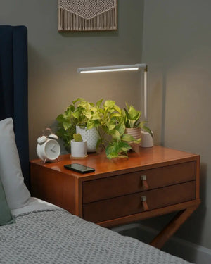 Wooden nightstand with plants, clock, white Soltech Versa and phone in a bedroom setting