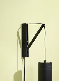 Black Soltech Pinocchio wall mount and black Soltech Aspect against a yellow background.
